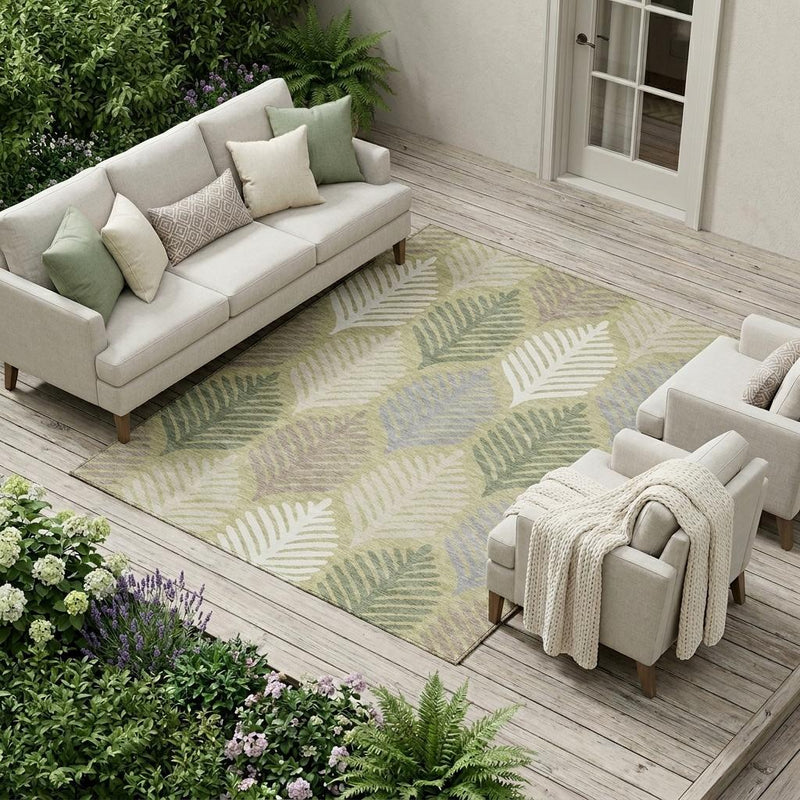 Indoor outdoor area rug with muted green and ivory leaf motif, shown on a covered patio