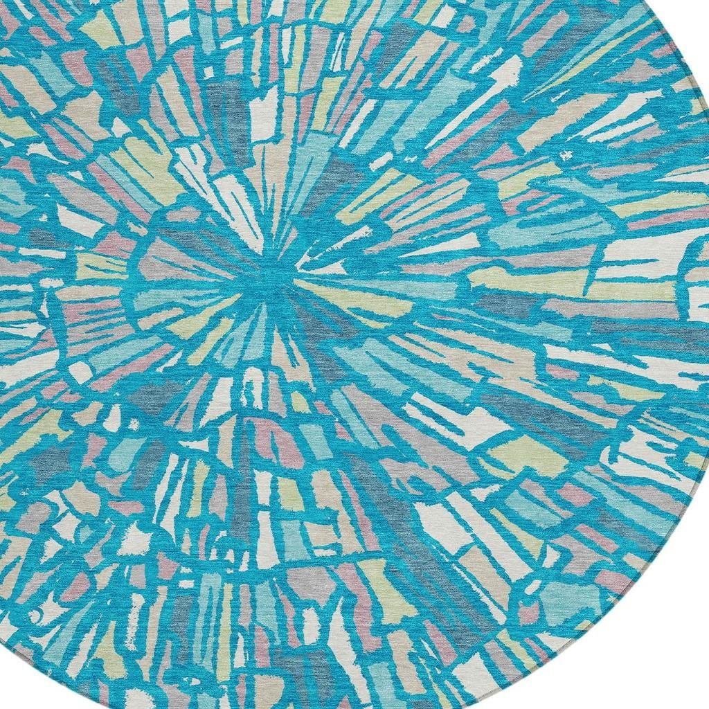 Round abstract rug with teal and blue sunburst pattern, cream lines and green tint.