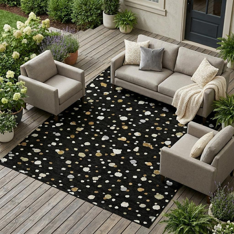 Geometric outdoor area rug in black with white and gold speckled shapes on deck.