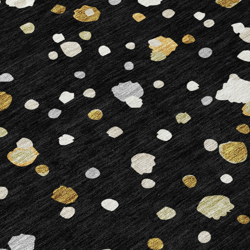 Textured geometric area rug close-up: black background with white and gold scattered shapes.