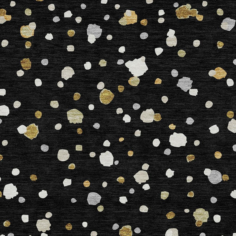 Close-up geometric area rug pattern on black with white and gold speckled shapes.