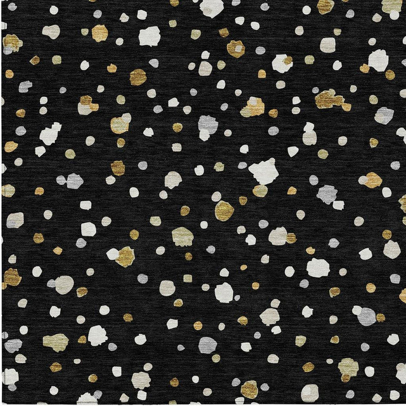 Geometric area rug with black base and dense scattered white and gold speckled pattern.