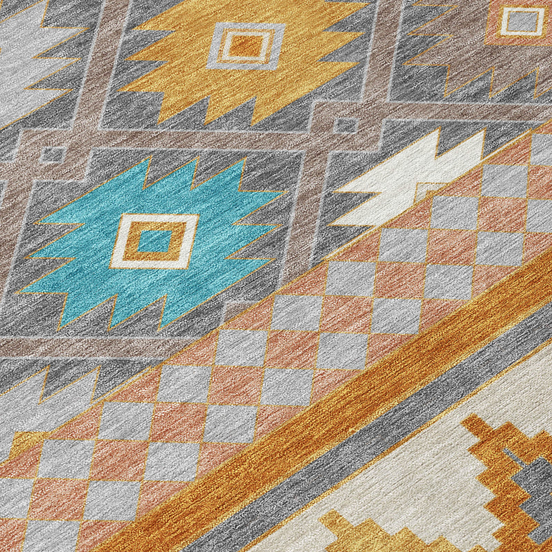 Close-up of gray area rug with diamond, chevron, and check patterns in teal and orange