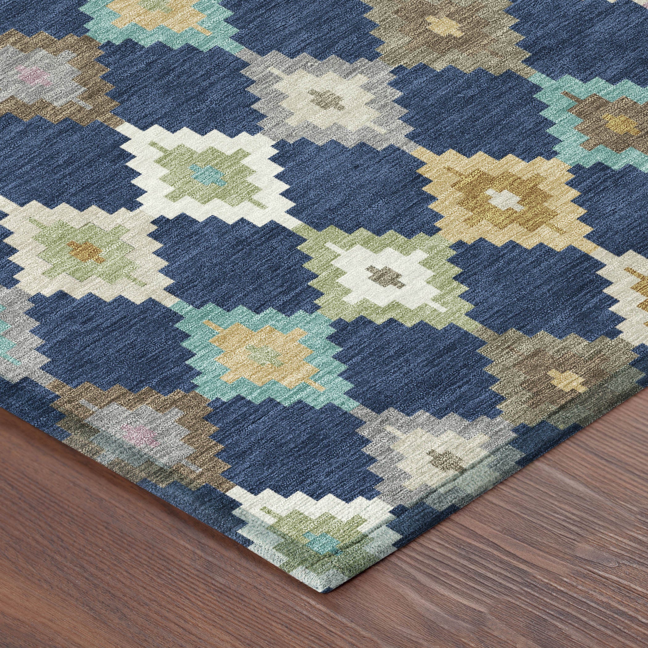 Corner view of navy blue aztec area rug with geometric diamonds in cream, teal, tan, gold