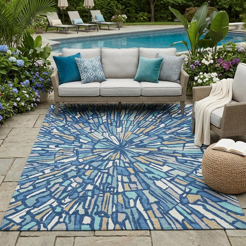 Outdoor area rug with blue, teal, and cream abstract sunburst pattern.