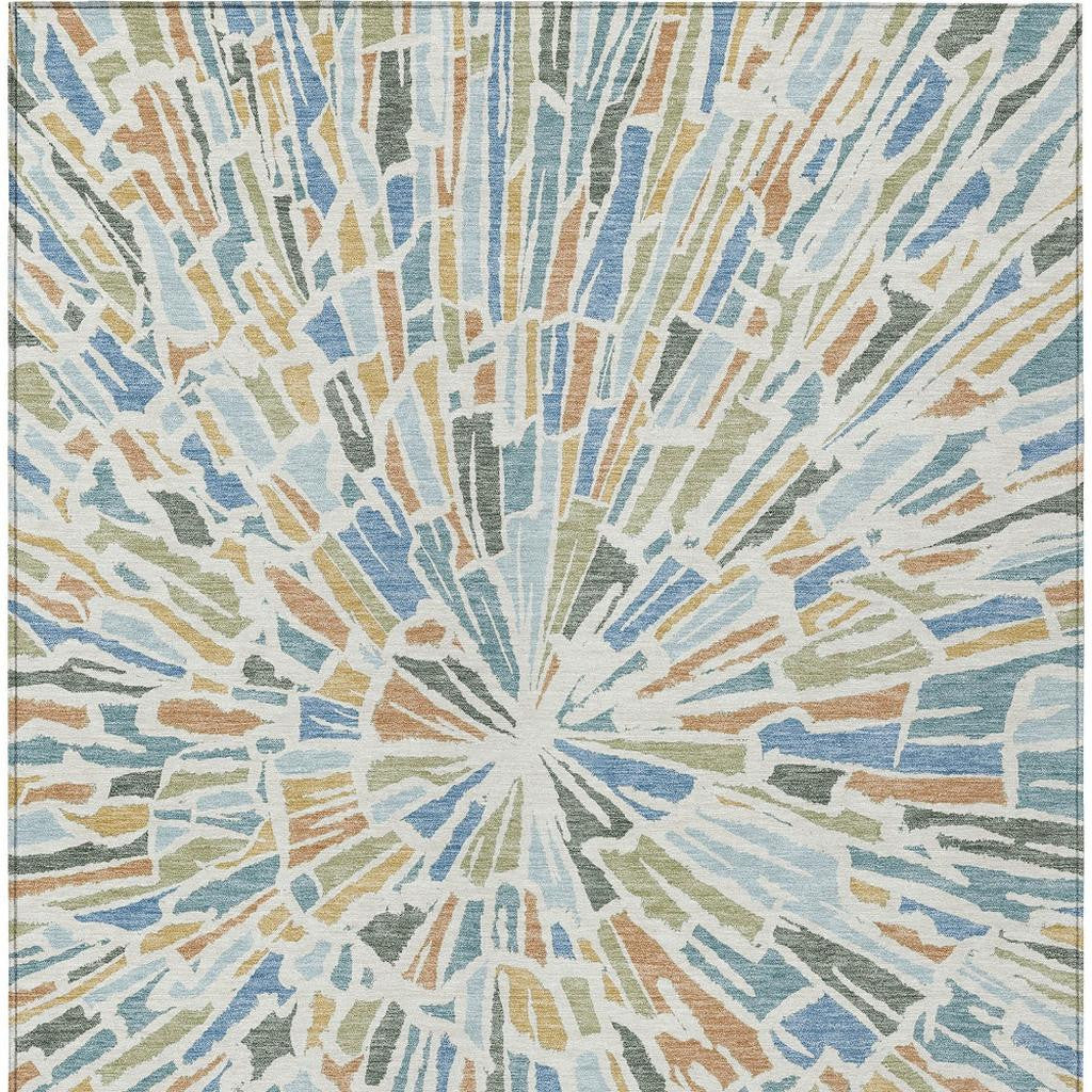 Blue abstract area rug featuring a centered sunburst pattern with beige and muted green accents