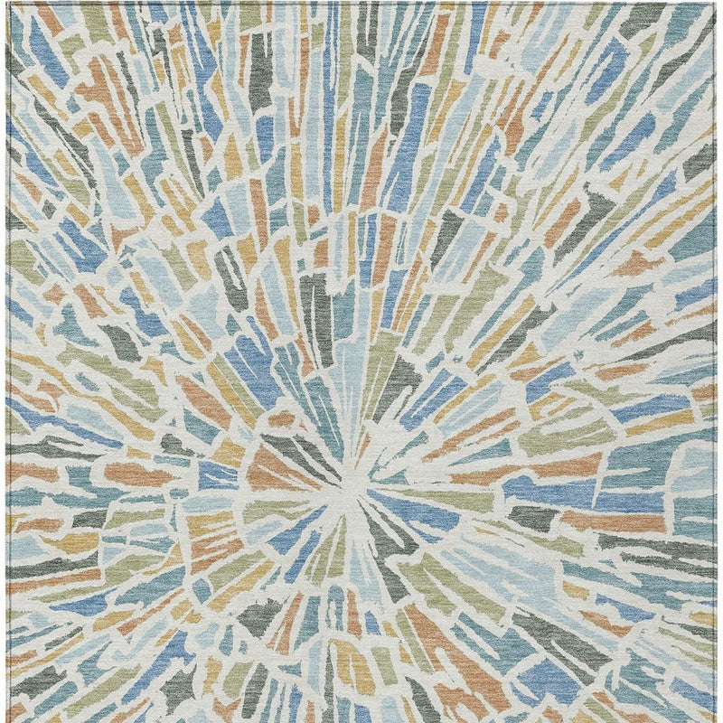 Blue abstract area rug featuring a centered sunburst pattern with beige and muted green accents