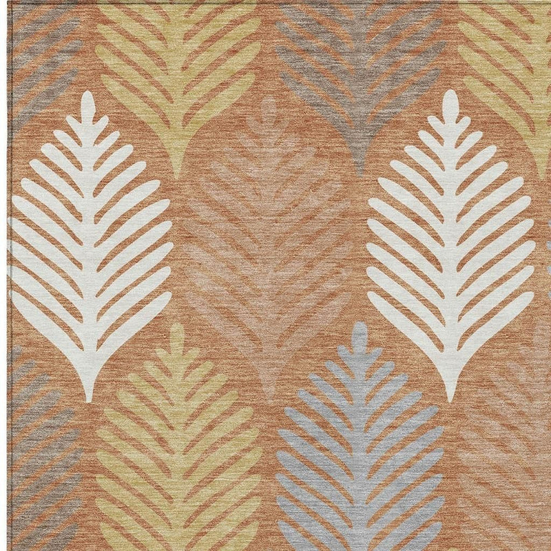 Close-up of orange and copper rug with cream leaf silhouettes and gray lines