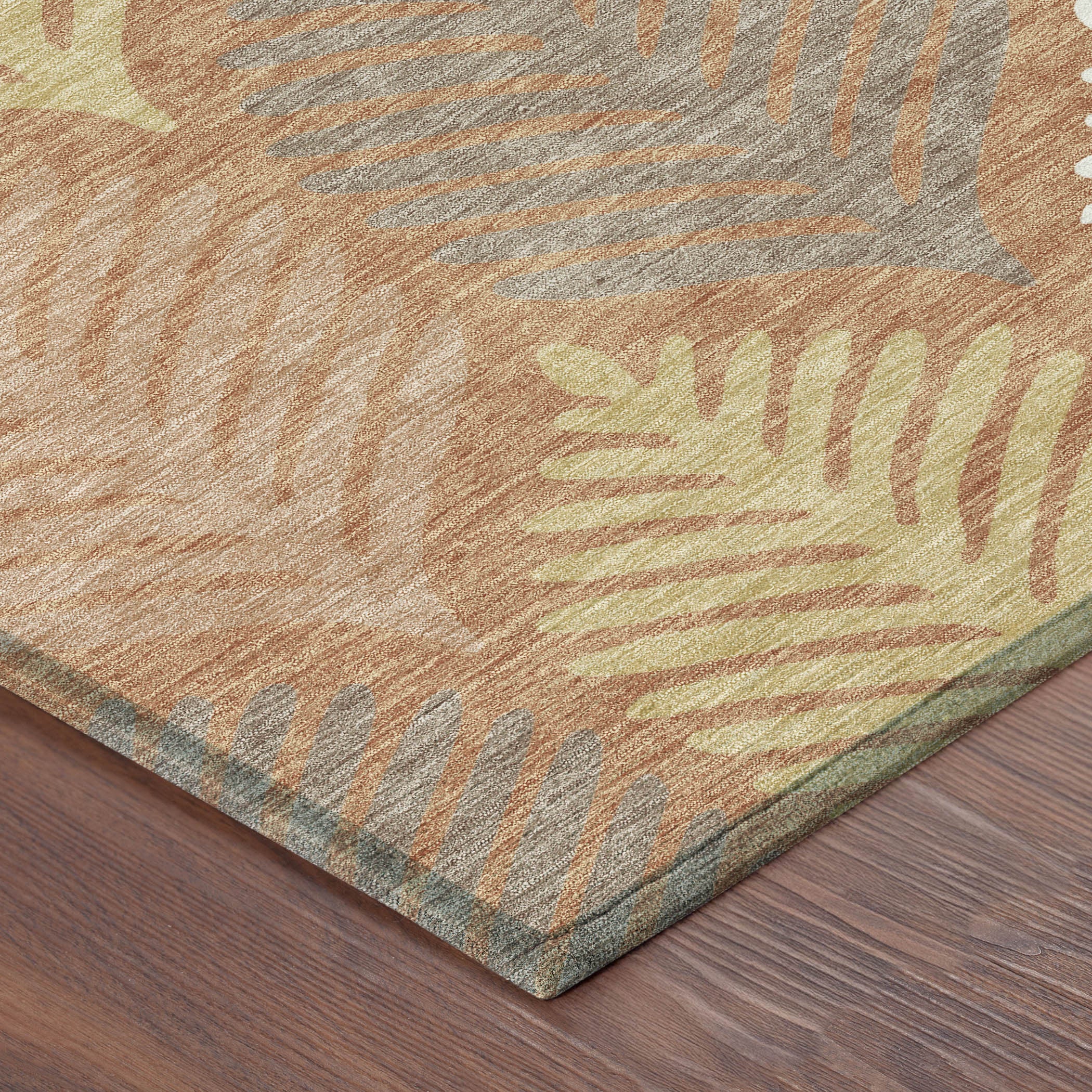 Corner view of orange-copper area rug with leaf pattern and textured weave edge
