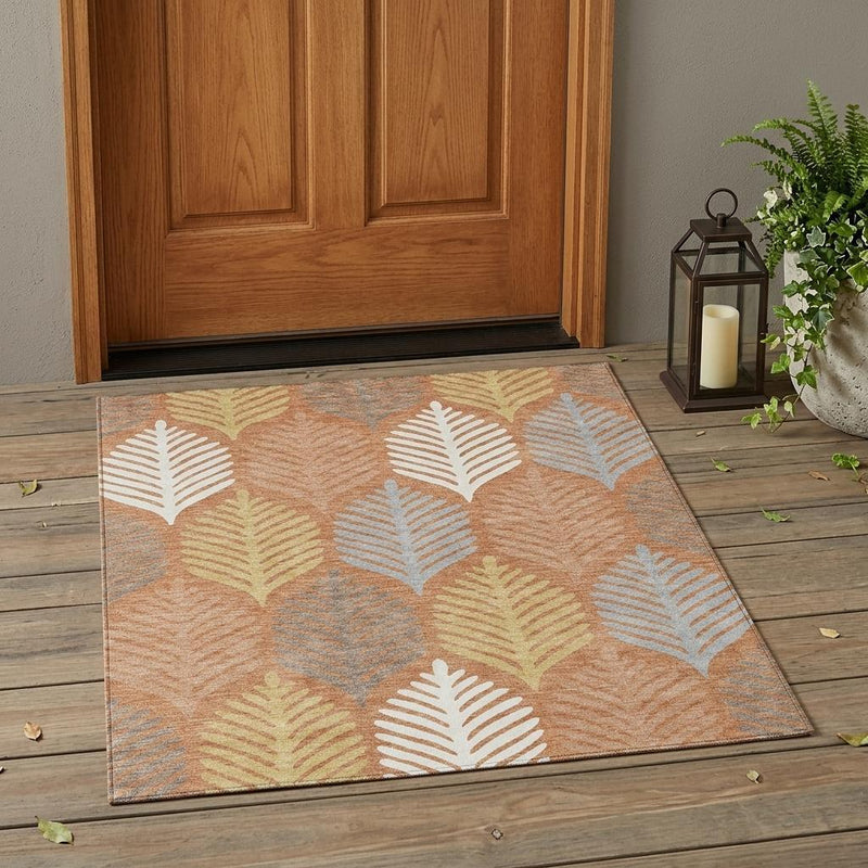Washable indoor/outdoor area rug with orange-copper base and white leaf pattern