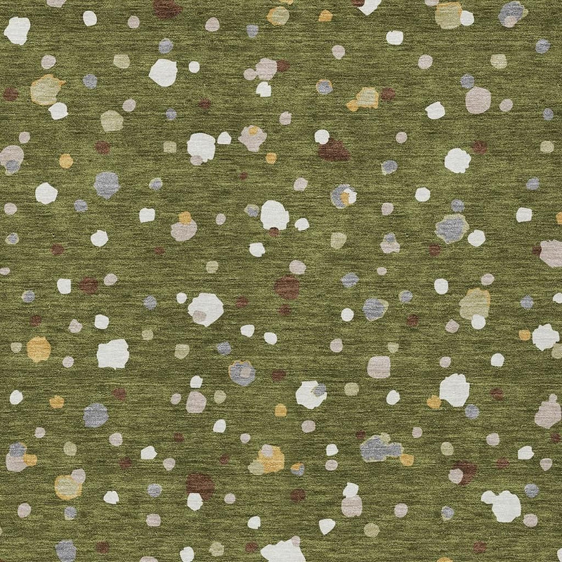 Olive green area rug close-up showing scattered white speck shapes and muted colored flecks