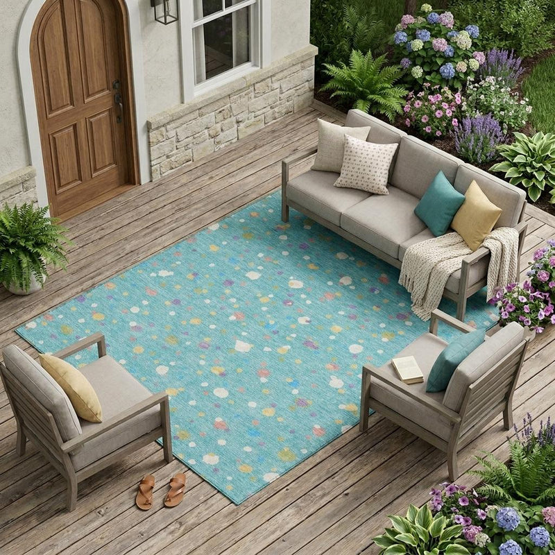 Teal blue outdoor area rug with multicolor geometric dot pattern on wooden patio