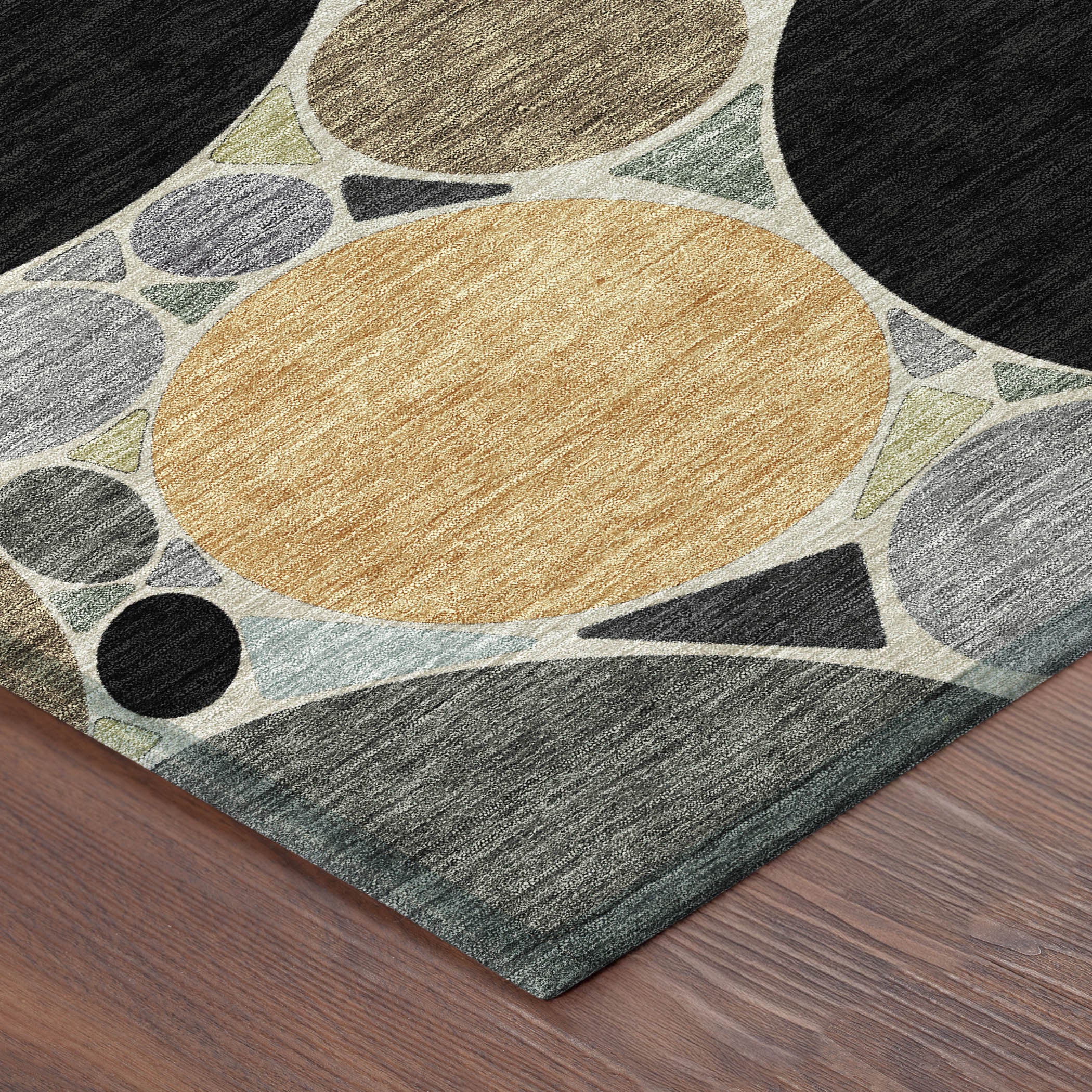 Geometric area rug corner view with gold oval center and black and gray circles