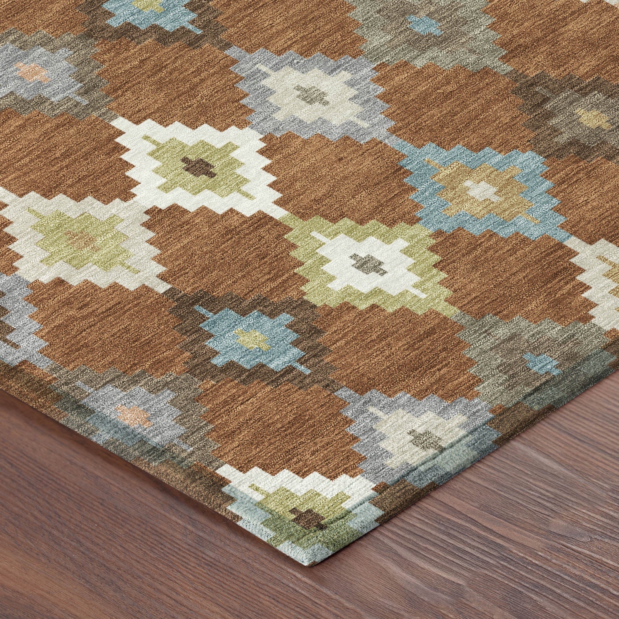 Brown round aztec rug corner with teal, gray, and cream zigzag diamond motifs