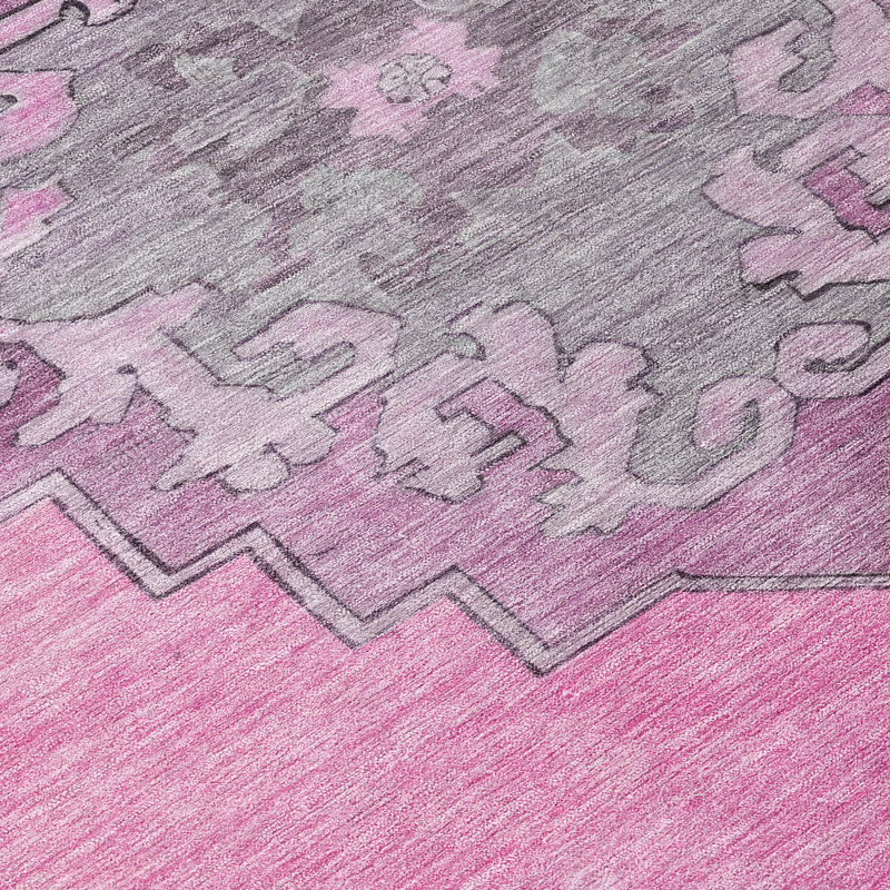 Close-up of pink geometric rug pile with gray pattern and stitched border lines