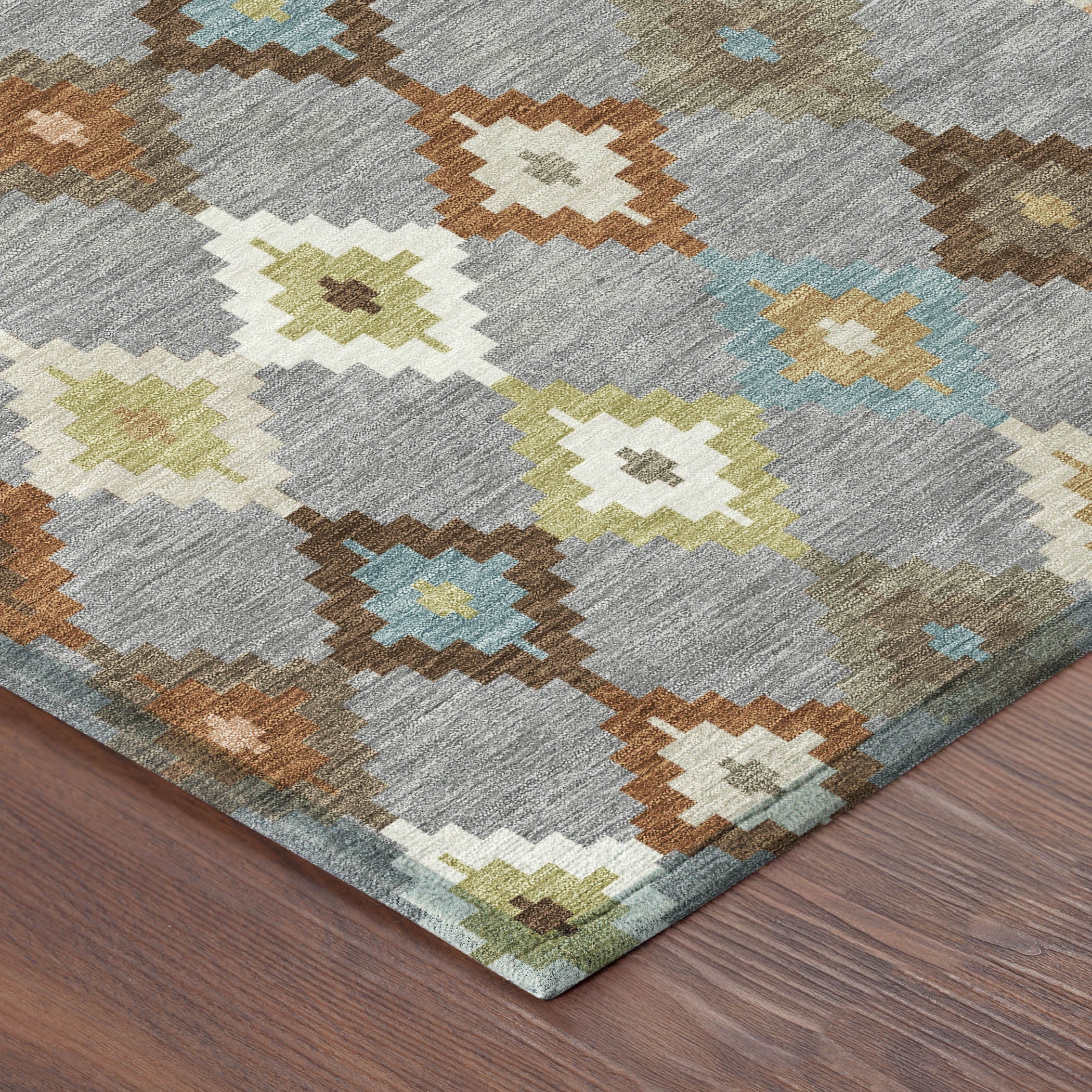 Gray area rug with orange, blue, green, and cream geometric diamond pattern closeup