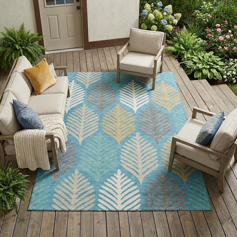 Teal blue outdoor area rug with ivory leaf pattern, placed on a wooden deck.