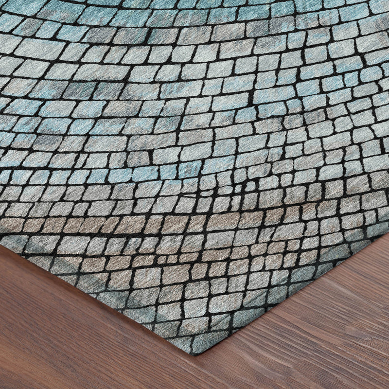 Corner view of teal and gray geometric mosaic area rug on wood floor