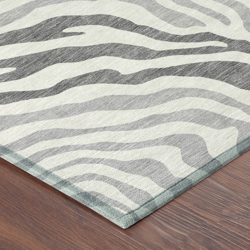 Corner view of gray and ivory zebra print area rug with flat, stitched edge.