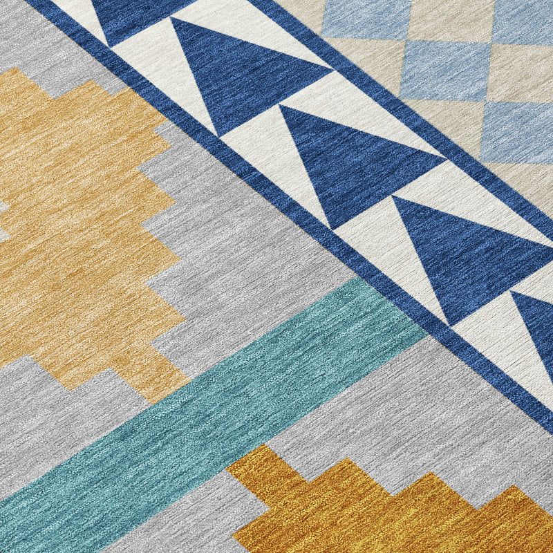 Close-up geometric area rug with navy chevrons, gray base, and tan and teal blocks