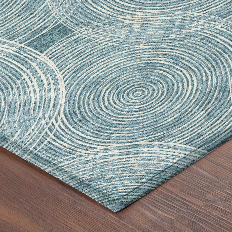 Teal blue and ivory geometric rug corner with concentric ring pattern and stitched edge