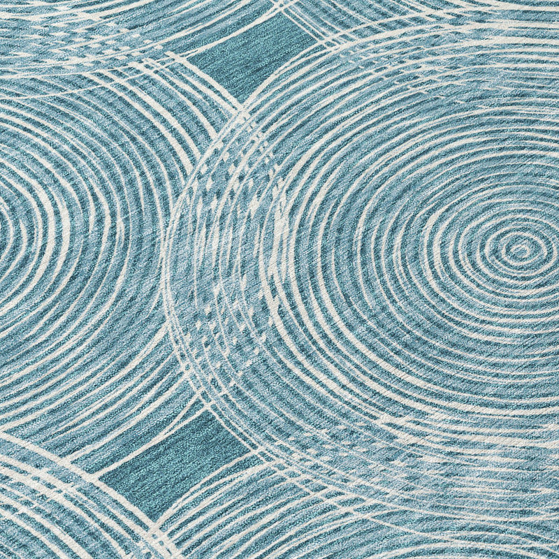 Teal blue area rug close-up with ivory ring lines and geometric border blocks