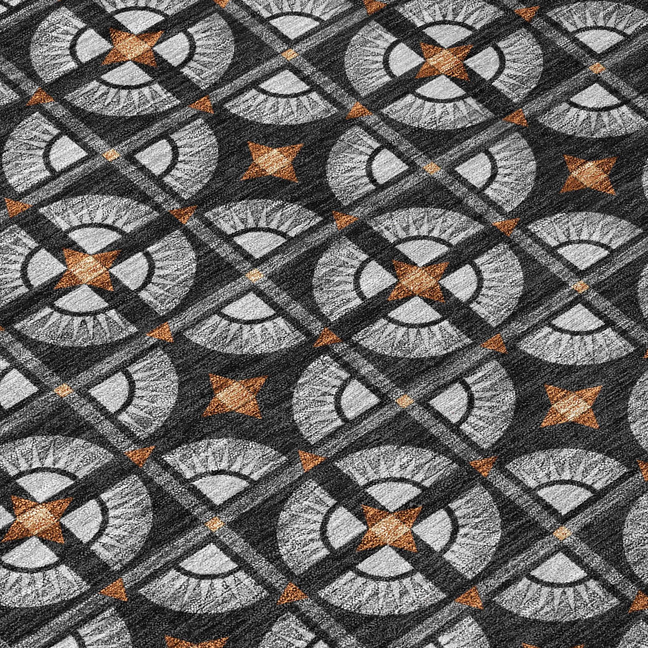 Geometric patterned rug in black, gray, and orange, featuring circular designs with stars and textured fabric.