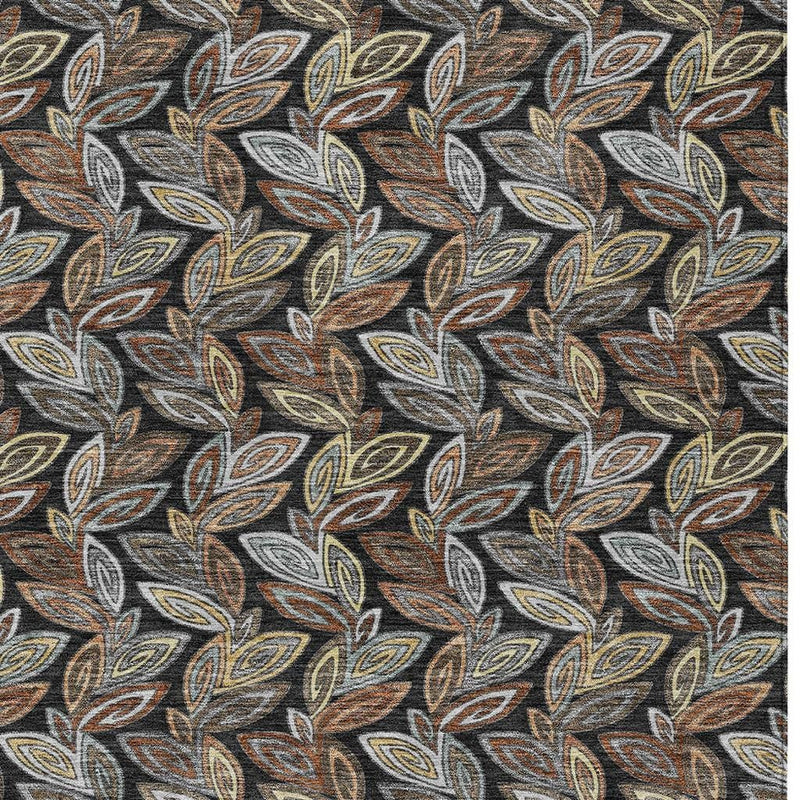 Close-up of dark charcoal rug with botanical leaf motif in gray, tan, and orange