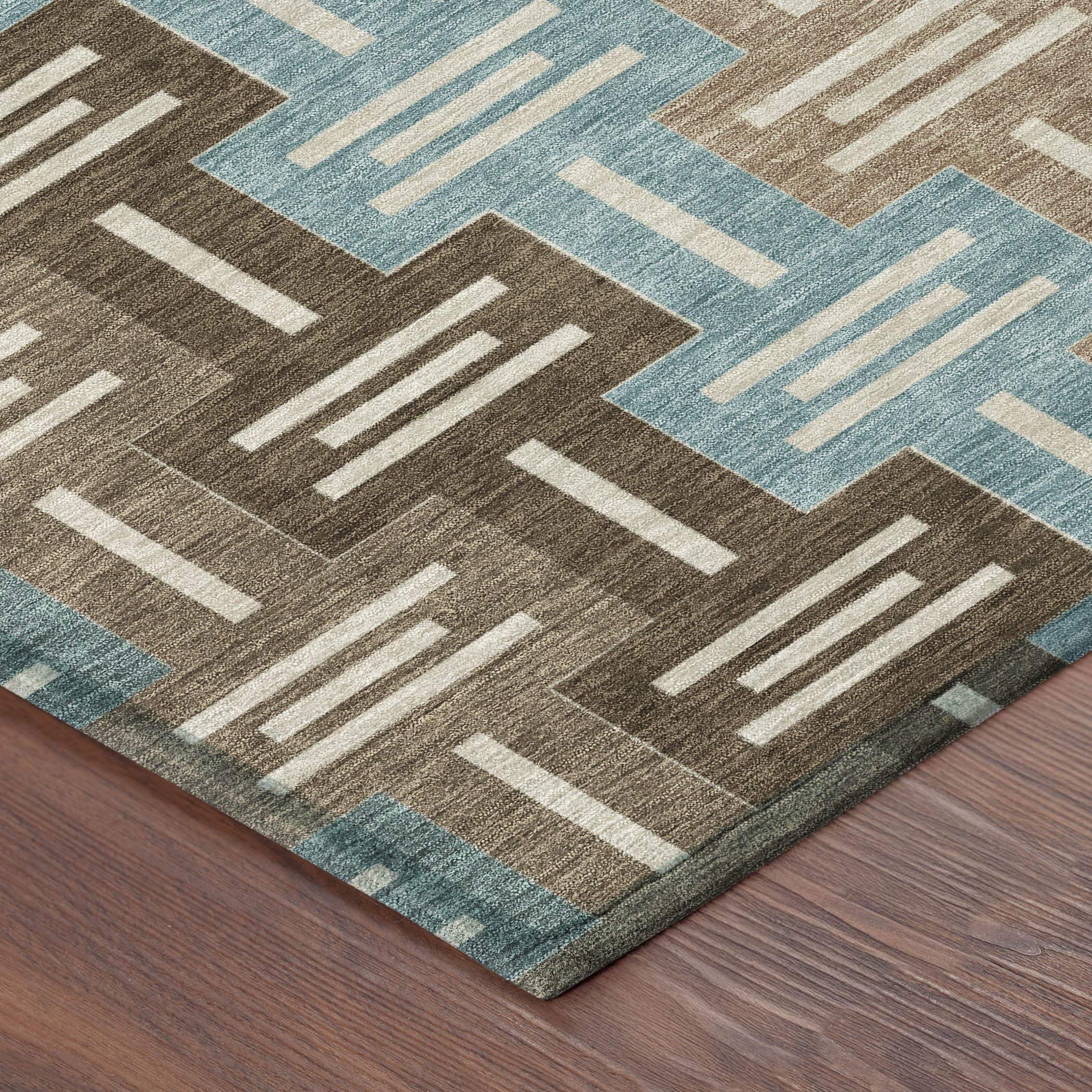 Multicolored geometric area rug in teal, brown, and cream, featuring a modern zigzag pattern on a soft, plush surface.