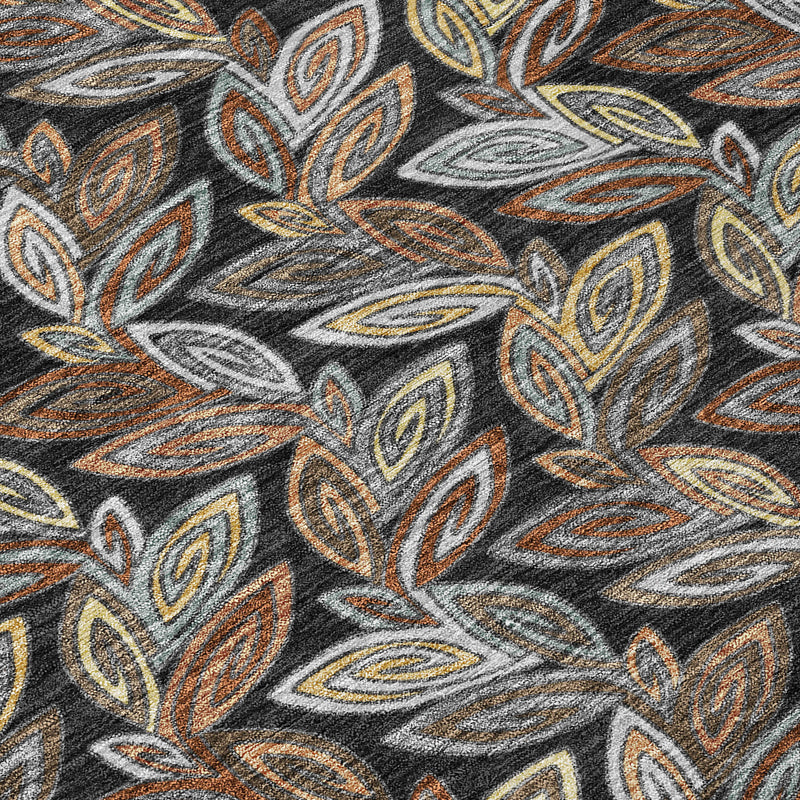 Charcoal gray rug with orange, yellow, and tan botanical leaf pattern close-up