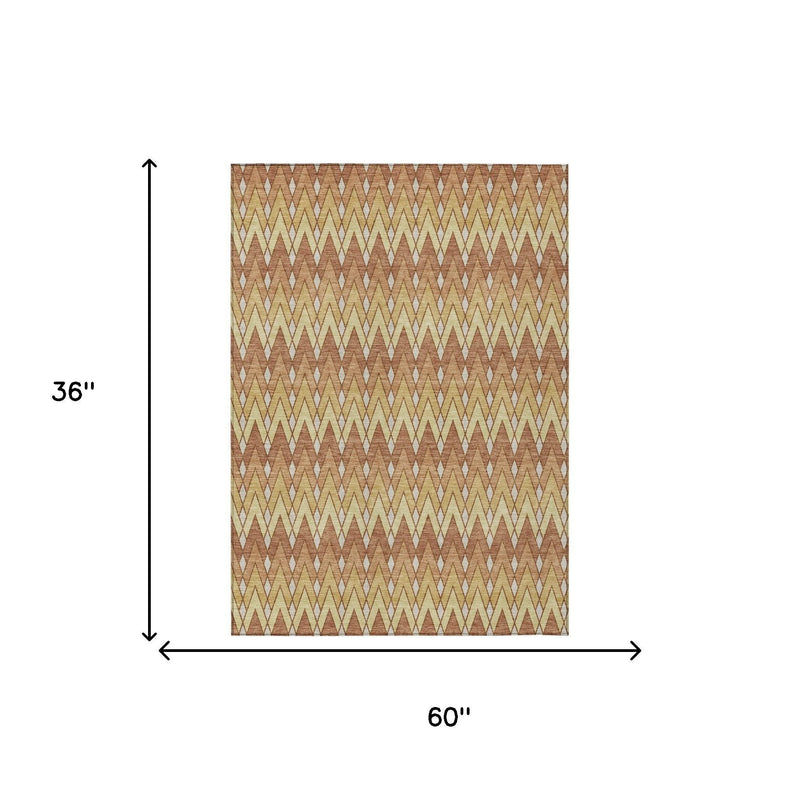 Geometric chevron area rug, 60 in x 36 in, orange and copper with cream accents.