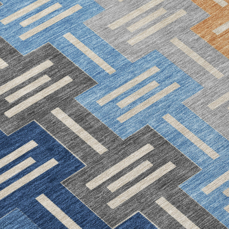 Geometric patterned area rug with blue and gray blocks plus tan accents on dark base.