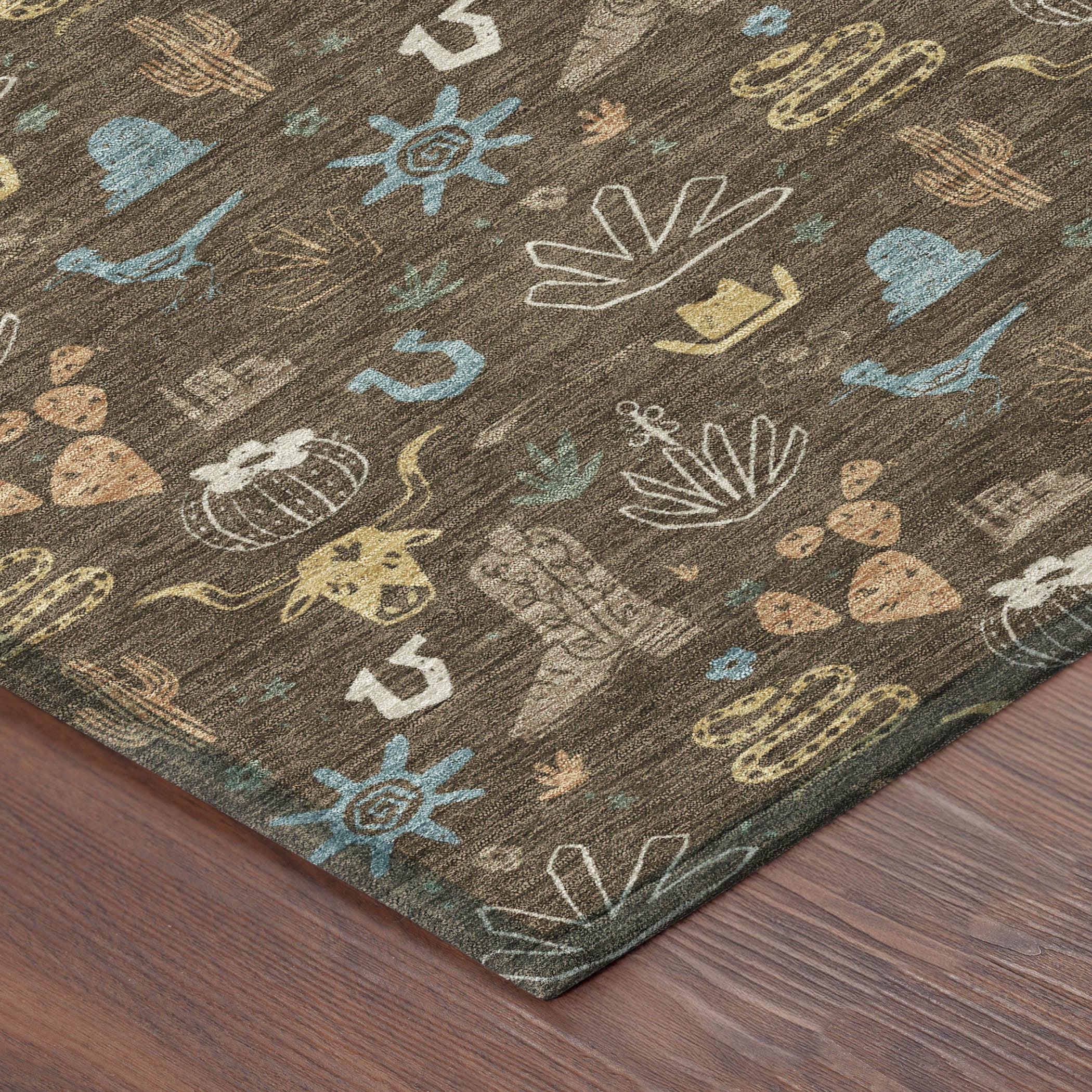 Corner view of a brown cactus motif indoor outdoor area rug with teal and tan pattern