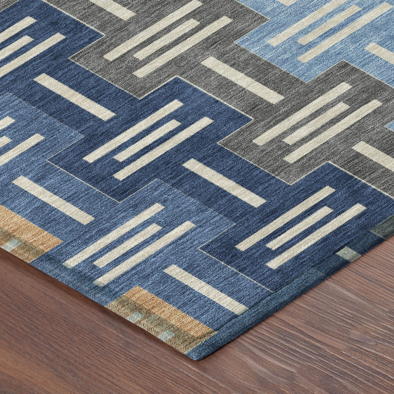 Indoor/outdoor area rug corner with blue, gray, tan geometric bar pattern and flat weave.