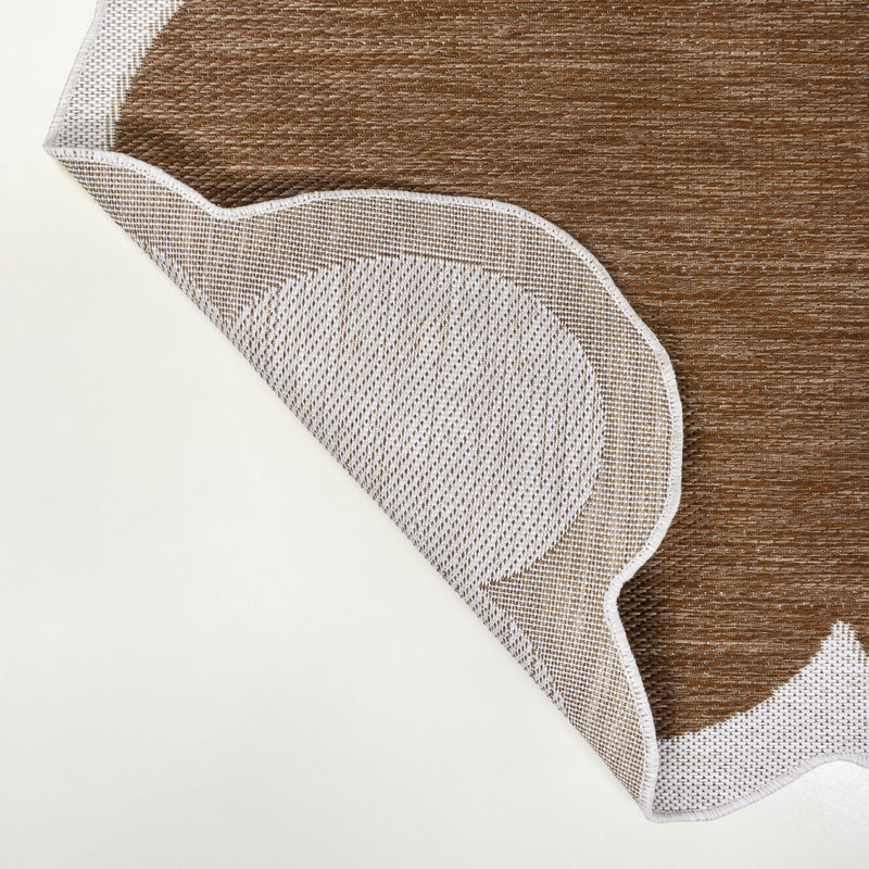 Corner view of area rug showing stitched cream border and brown woven surface