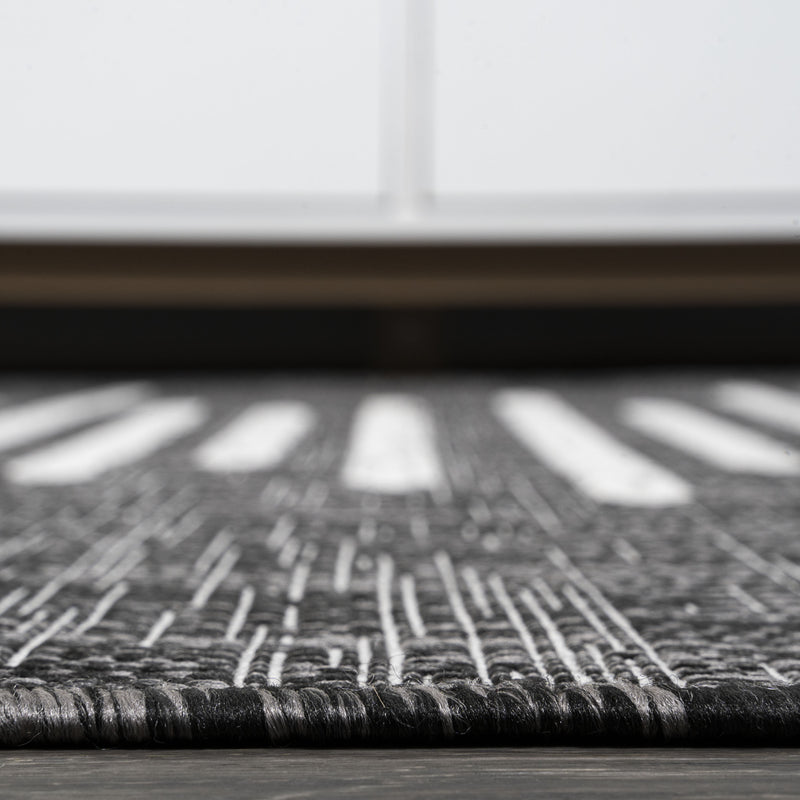Black rug with ivory horizontal stripes and textured flat weave, close-up view