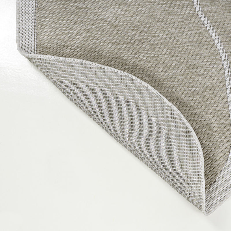 Beige and cream area rug corner with textured weave and stitched binding edge