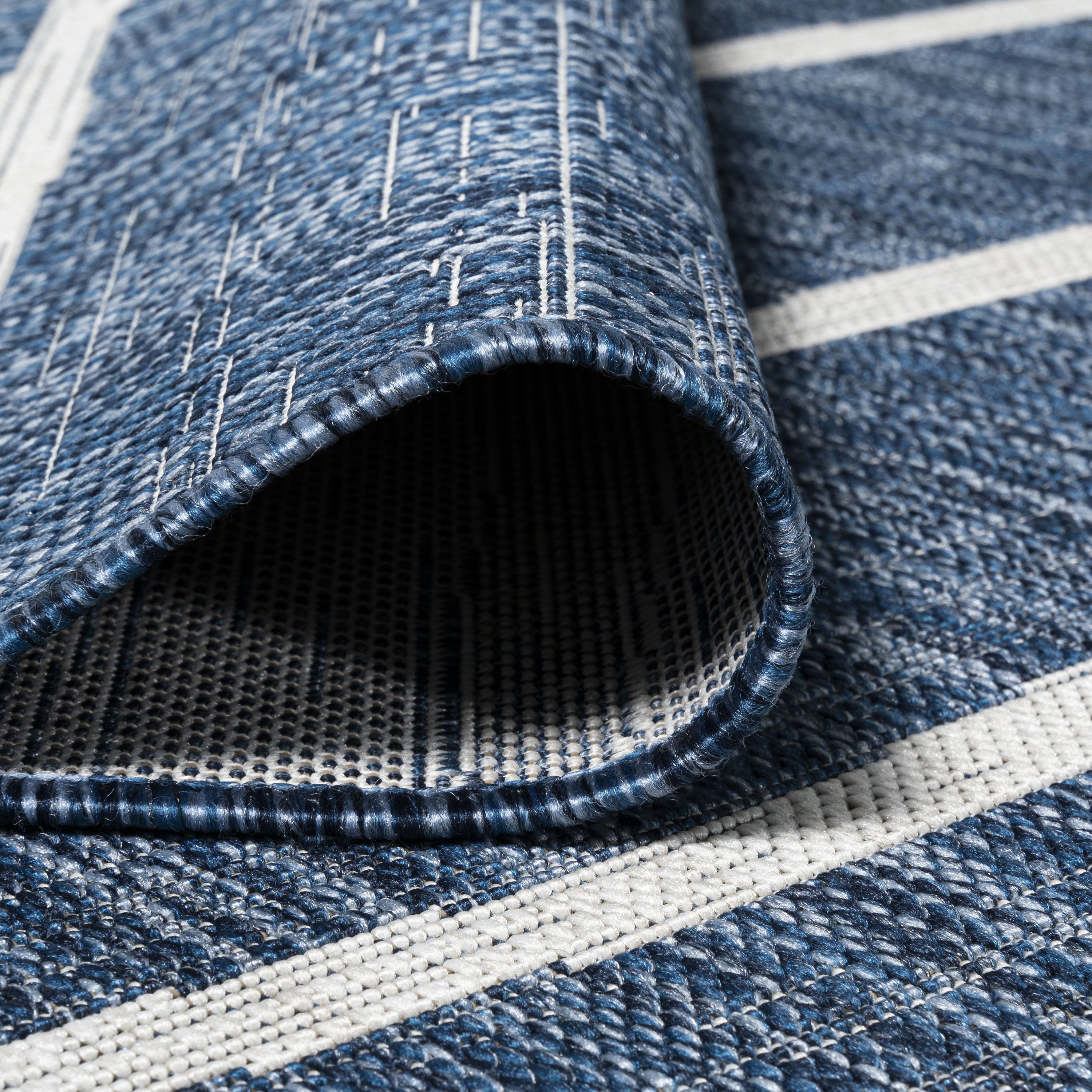 Blue and ivory striped area rug corner with dark binding and textured woven edge