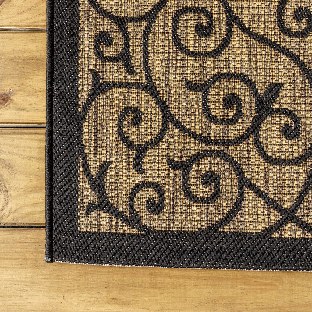 Runner rug corner close-up: black edging with tan weave and swirling motif