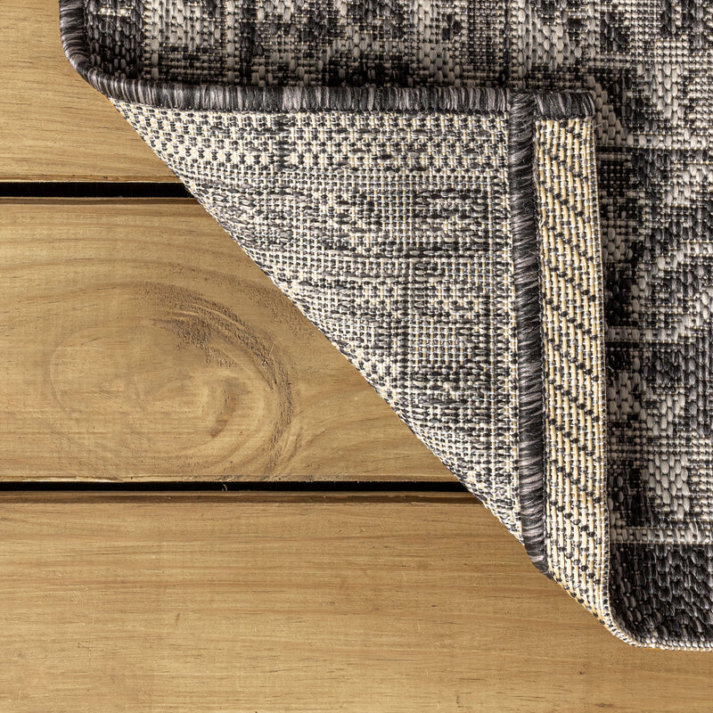 Corner detail of gray and black medallion rug with textured woven edge