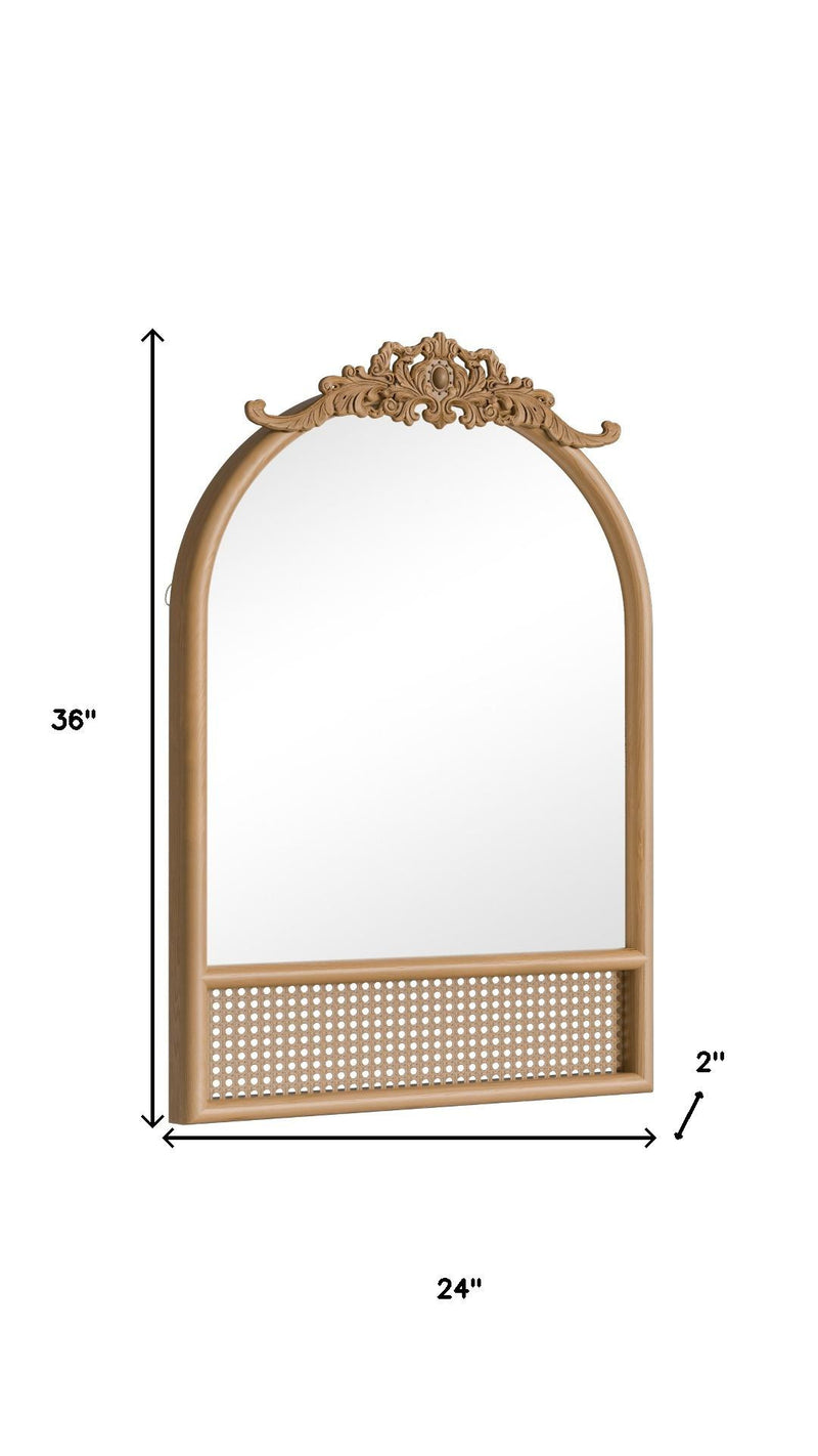 Arched mirror in brown wood frame with ornate scroll top and perforated rattan panel