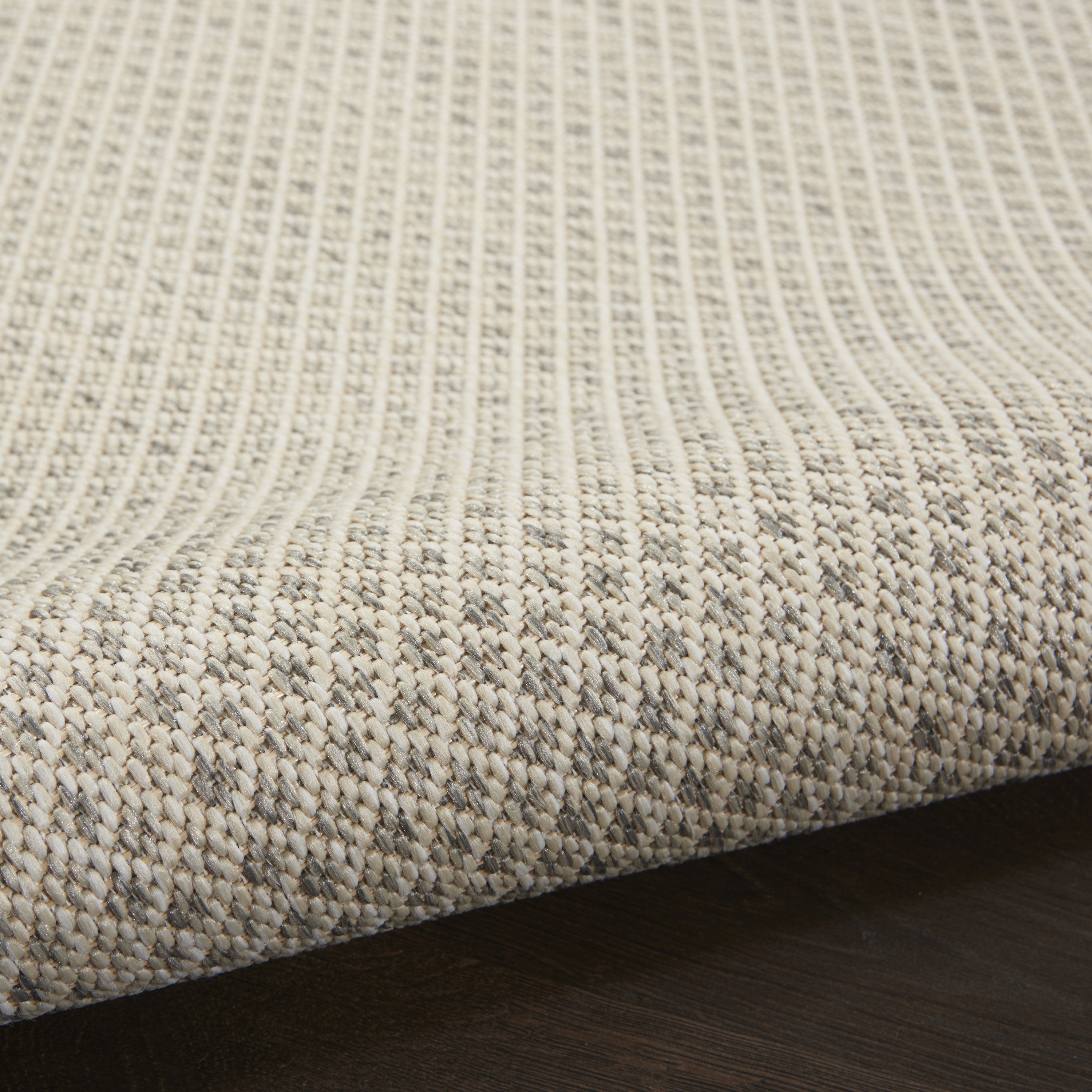 Woven rug pile detail with tightly textured loops in light ivory and gray