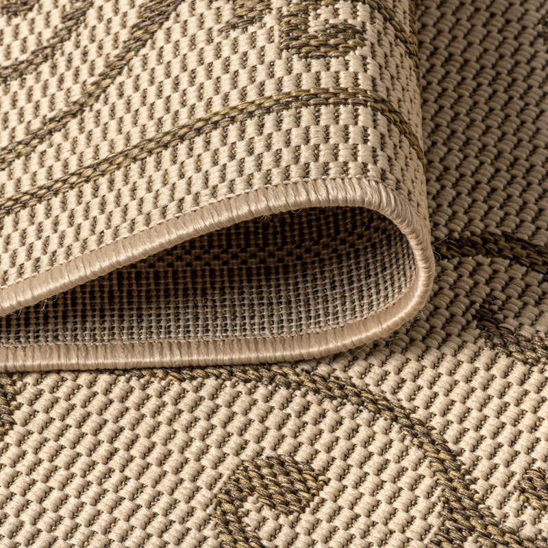 Beige rug with brown pattern detail and stitched edge binding at the corner.