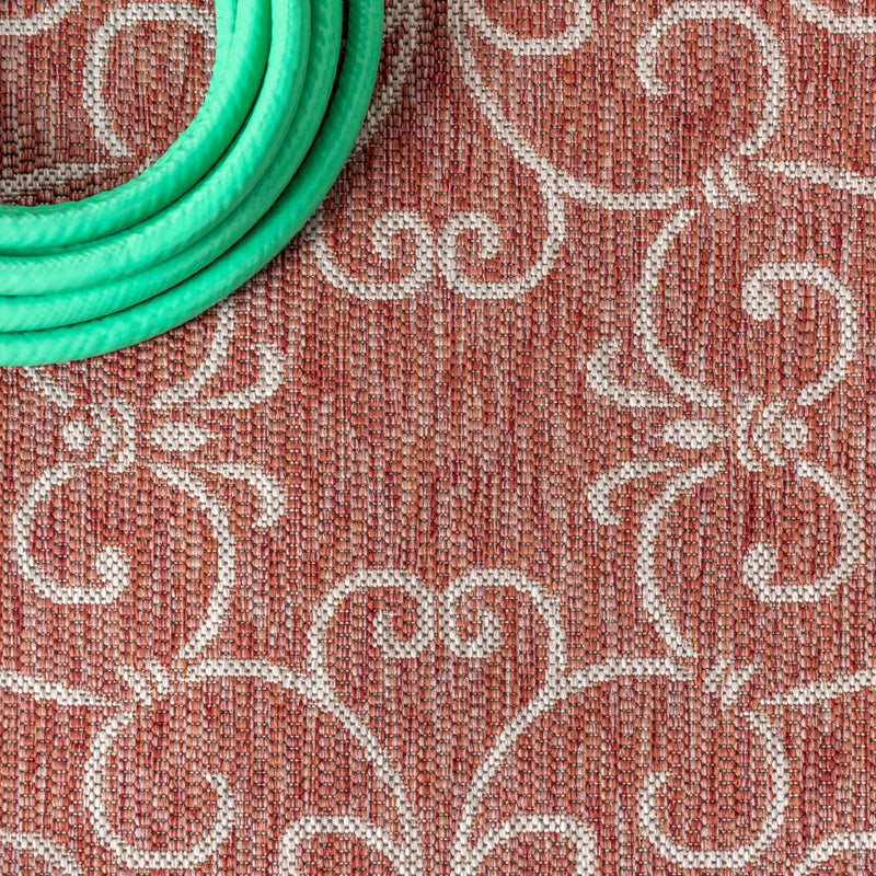 Indoor/outdoor area rug close-up texture with red-brown and light beige ornate motifs