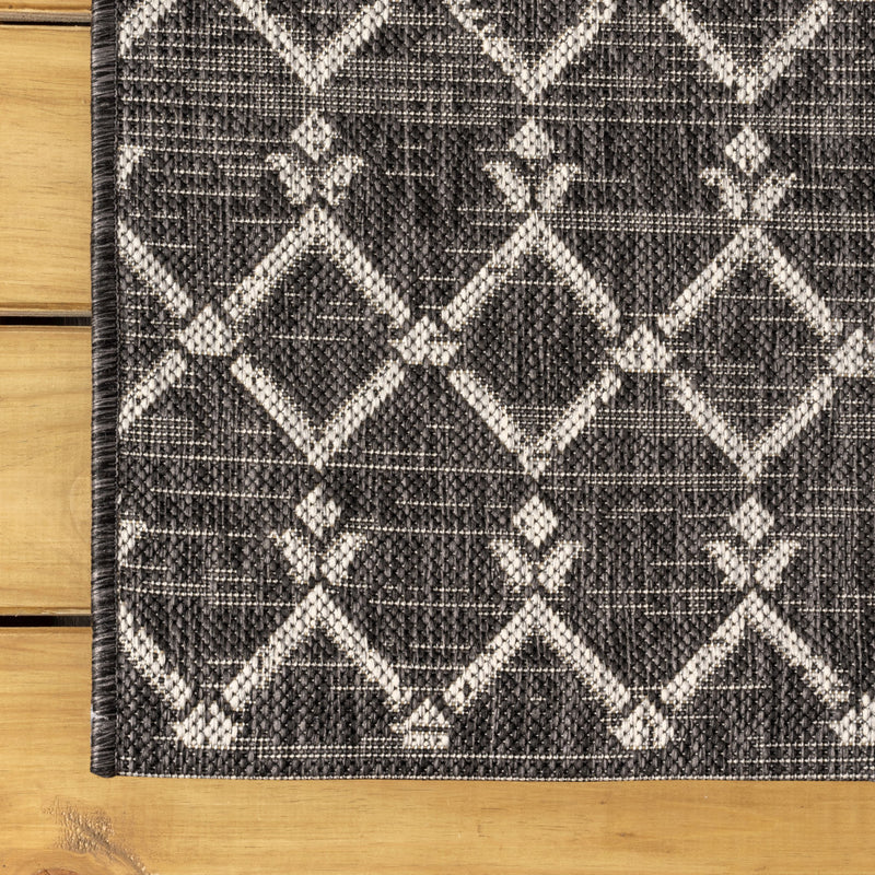 Round black and gray trellis area rug edge with diamond pattern and textured weave