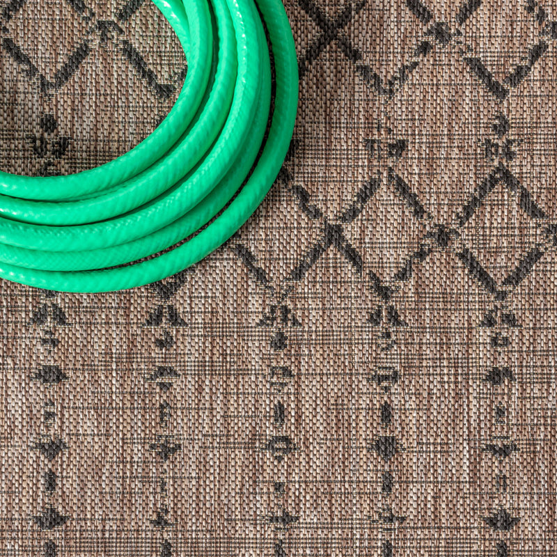 Beige round rug with black diamond trellis pattern; close-up view.