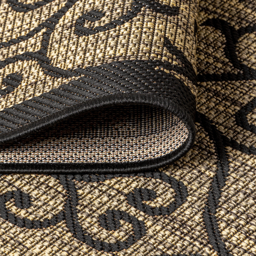 Rolled edge of black-and-khaki rug with woven texture and scroll geometric motifs