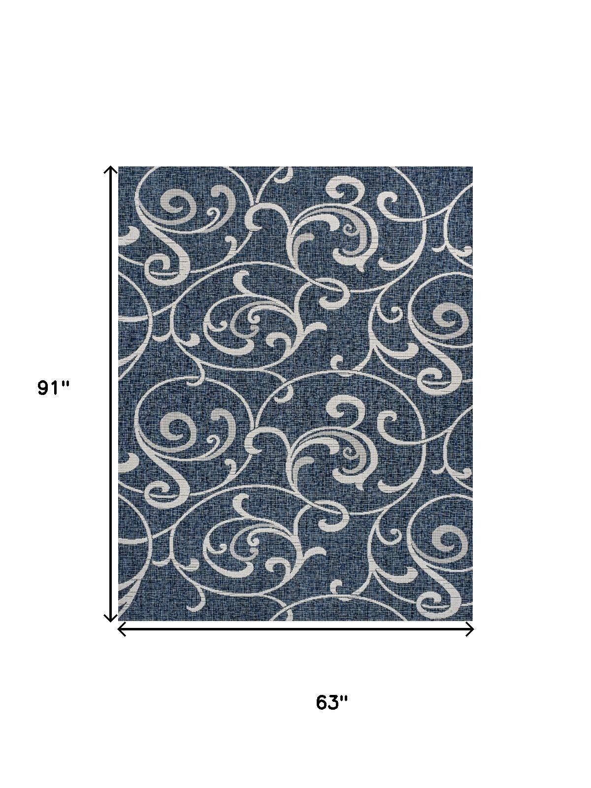 Navy blue area rug with cream swirling floral pattern, flat woven look