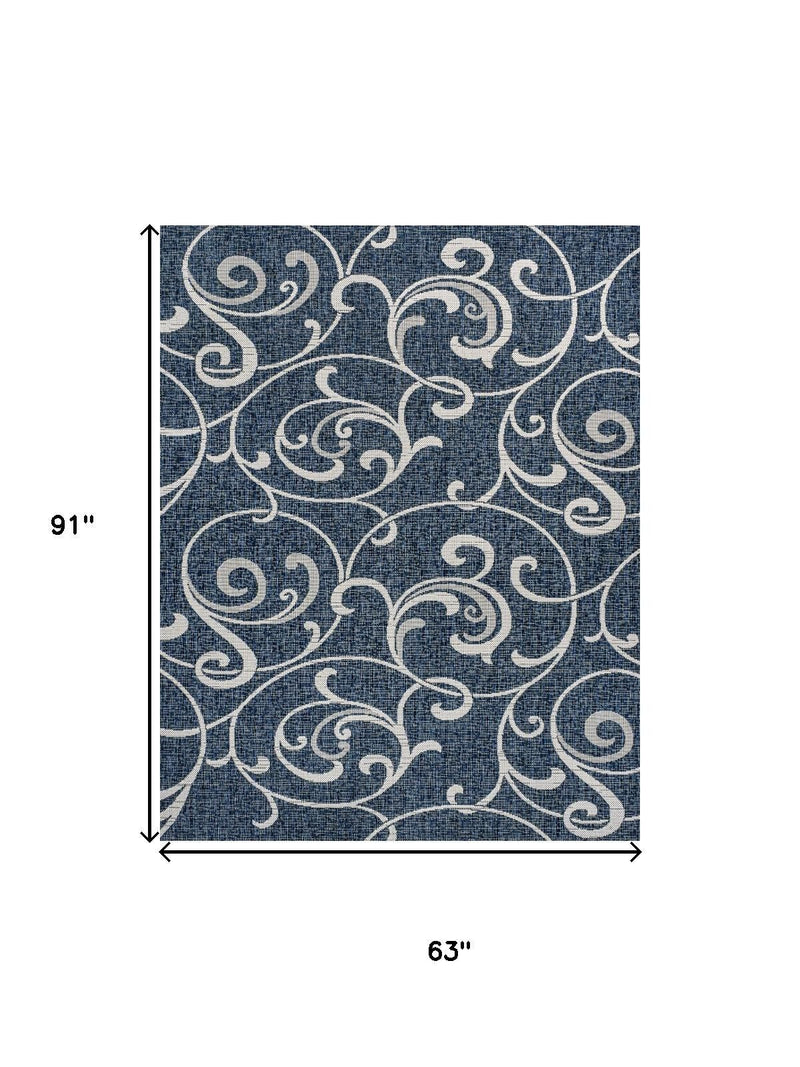 Navy blue area rug with cream swirling floral pattern, flat woven look
