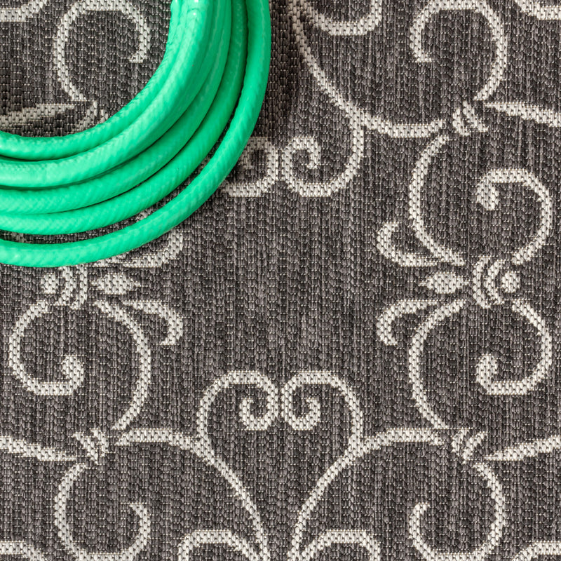 Close-up of black and gray rug texture with white scroll medallion motifs